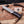 A fixed-blade knife with a patterned Damascus-style steel blade and a dark wood handle lies on a wooden surface with wood shavings and antlers around it. A small card reading Stag & Steel Knives is visible behind the knife.