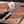 Gloved hand gripping lacewood handle of full tang D2 hunting knife over board