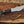Full tang D2 tracker knife with black Micarta handle, mirror polished blade, notched spine, and paracord on wood background