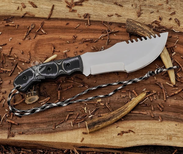 Full tang D2 tracker knife with black Micarta handle, mirror polished blade, notched spine, and paracord on wood background