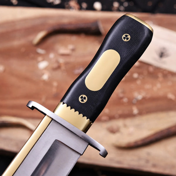 Black G10 grip with brass engraving plate viewed from blade side on D2 bowie