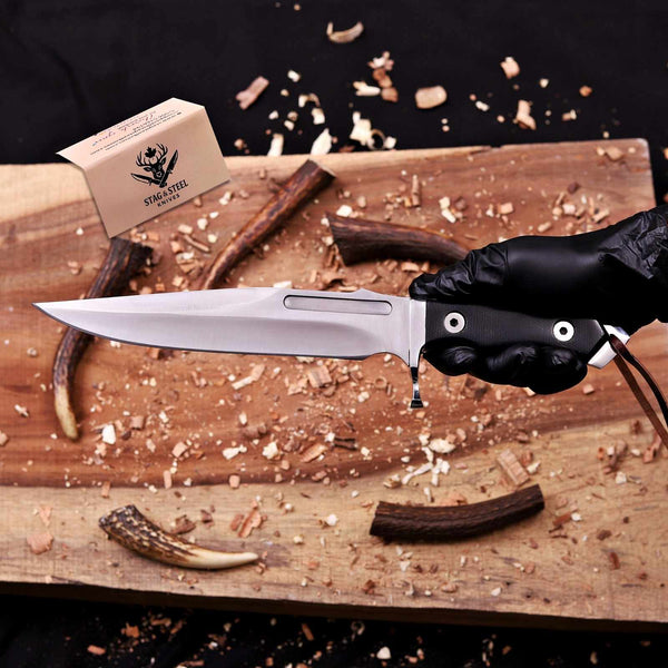 Handmade D2 steel bowie knife held by the black micarta handle