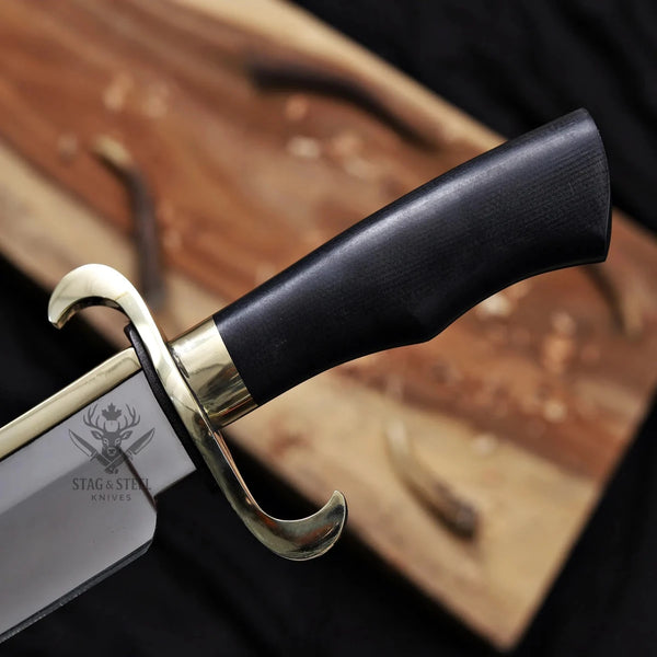 Handmade Musso bowie knife held in hand showing brass back strap on D2 blade
