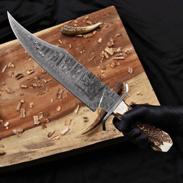 Juan Padillo Damascus Bowie knife held in a gloved hand, clip-point blade detail