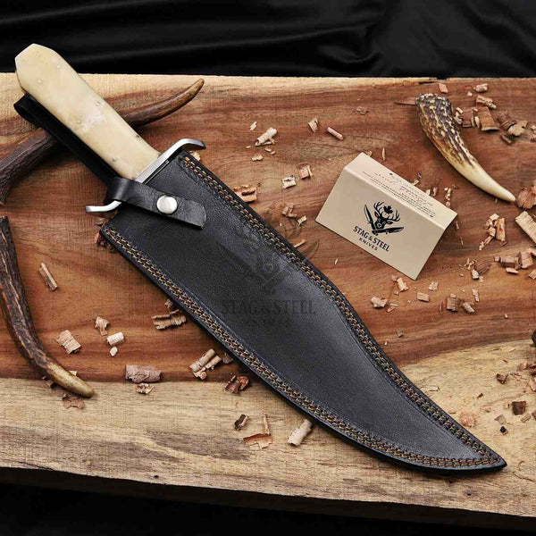 D2 Bowie knife in a black tooled leather sheath beside a Stag Steel Care Card.