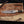 copper damascus bowie knife with antler handle laying wooden backround