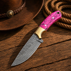 Pink turquoise cowboy knife beside black leather pancake sheath with basketweave tooling