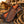 A western-style leather sheath with a tooled diamond pattern and a wooden handle, displayed on a rustic wooden post with a rope coil in the foreground and a horse in the blurred background.