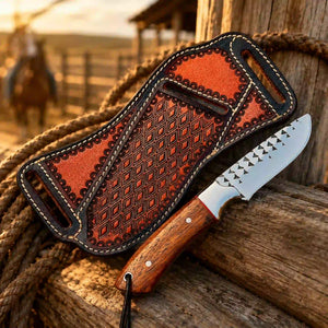A fixed-blade knife with a patterned brown leather sheath and wooden handle, displayed on rustic wood with a rope and a blurred outdoor western background.