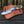 Knife with wooden handle and leather sheath on a wooden surface with a forest background