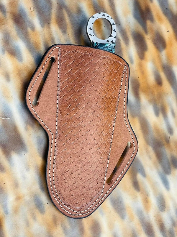 A brown leather key pouch with a textured basketweave pattern, white contrast stitching, and a silver metal ring, displayed on a leopard-print background.