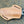 A tan leather knife sheath with a textured basketweave pattern, yellow stitching, and a silver metal keyring, shown on a dark textured background.