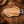 A tan leather knife sheath with a textured basketweave pattern, yellow stitching, and a silver metal keyring, shown on a dark textured background.