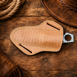 A tan leather knife sheath with a textured basketweave pattern, yellow stitching, and a silver metal keyring, shown on a dark textured background.