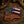 Two fixed-blade knives with Texas flag handle designs rest on a brown leather sheath over a rustic wooden surface, with a cowboy hat and rope partially visible in the background.