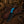 A fixed-blade knife with a textured black blade, a bright blue handle insert, and a dark wood handle, displayed on a brown leather sheath over a rustic wooden surface with western-themed props including a rope, hat, gloves, and horseshoe.