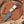 Damascus Cowboy Bull cutter  knife with a wooden handle and turquoise inlay in a pancake leather sheath on a wooden surface.