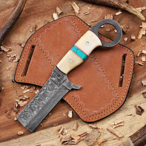 Damascus Cowboy Bull cutter  knife with a wooden handle and turquoise inlay in a pancake leather sheath on a wooden surface.