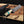 Hand holding a Damascus knife with a decorative handle against a dark background